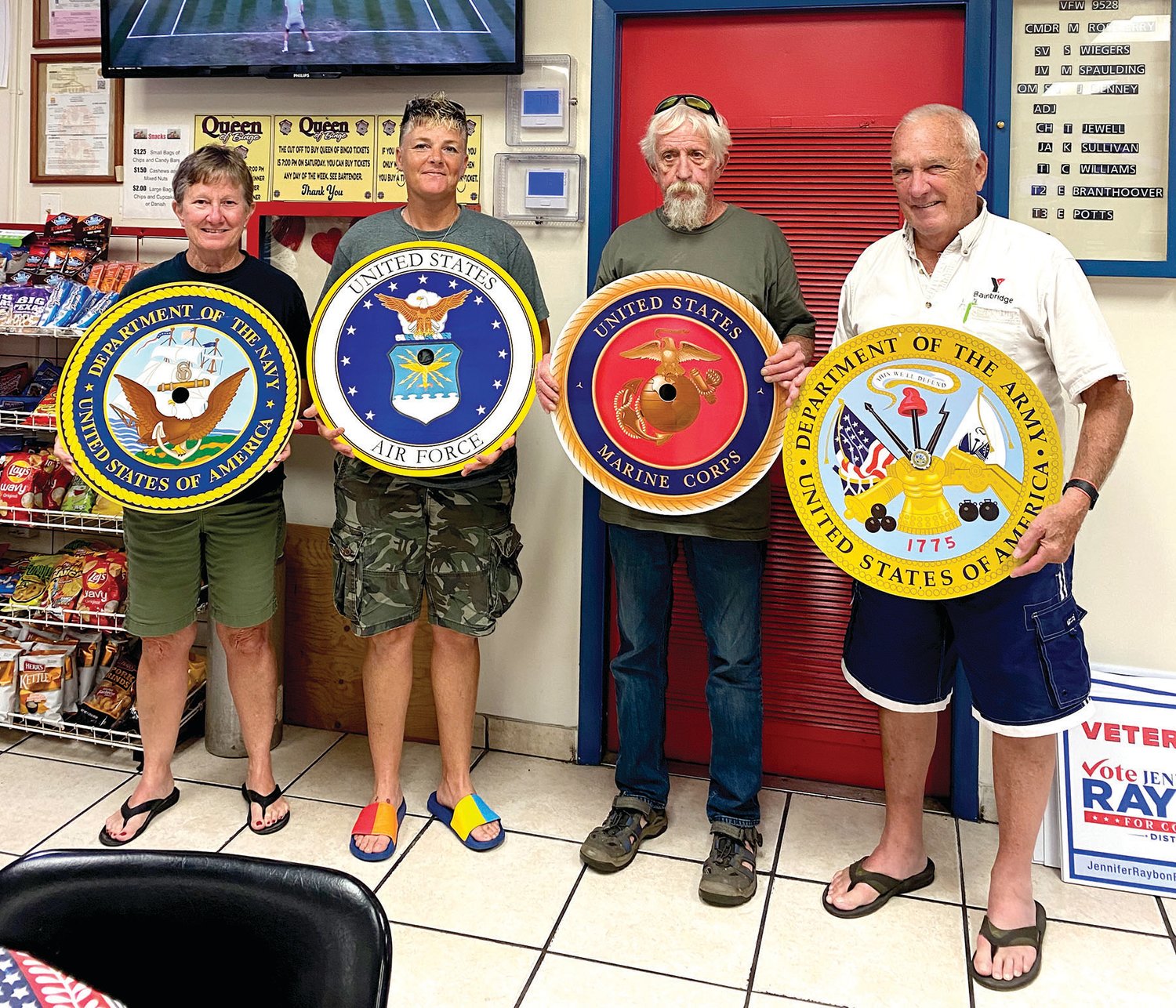 Pam Denny, Lori Barton, Commander Mike Roseberry and John Denny with the signs representing each branch of the military.